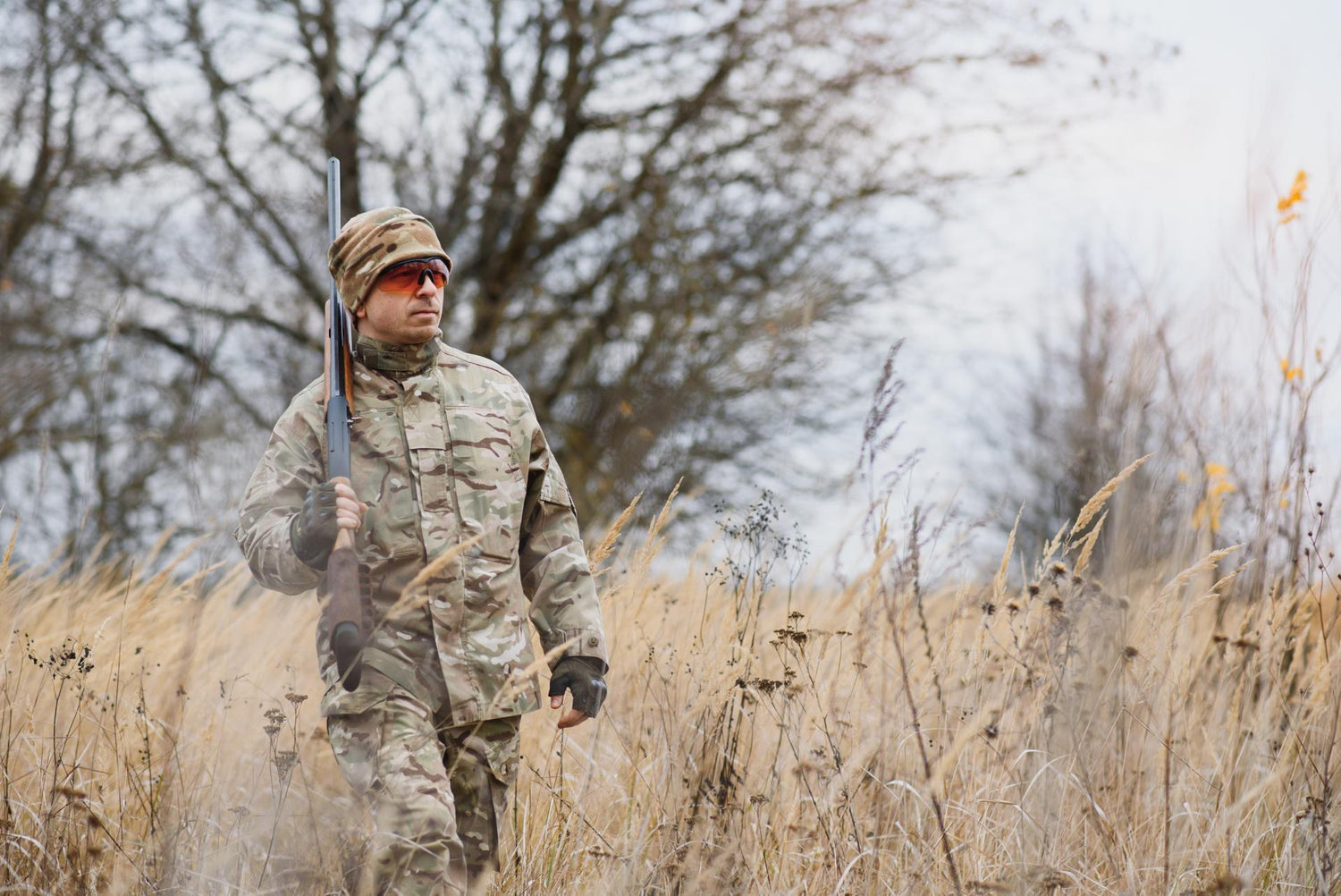 hunting, war, army and people concept - young soldier, ranger or hunter with gun walking in forest.