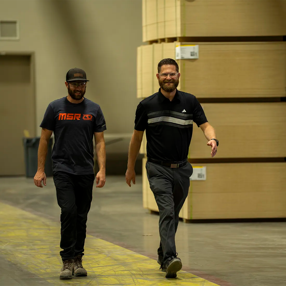 Two Liberty Safe employees are smiling and wlaking thorough the warehouse.